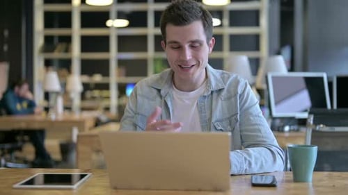 Young Designer Doing Video Chat on Laptop in Modern Office