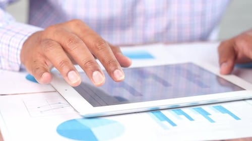 Man's Hand Working on Digital Tablet at Office Desk Using Self Created Chart