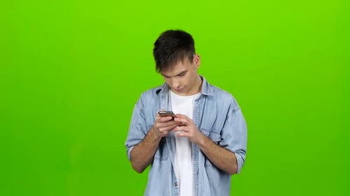 Man Looks at the Phone in the Photo, and Has Fun. Green Screen