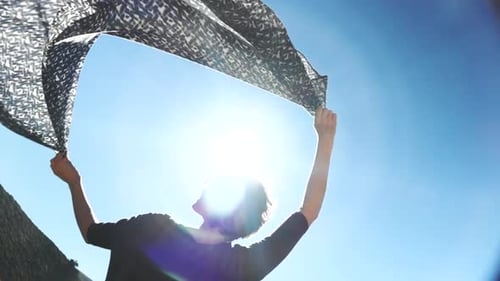 Woman Holds Scarf Up to Blue Sky