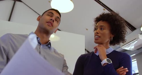 Mixed-race business people discussing over blueprint in a modern office 4k