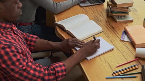 Top View Black Guy Student Writes in His Notebook