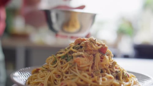 Chef sprinkles topping on seafood pasta dish