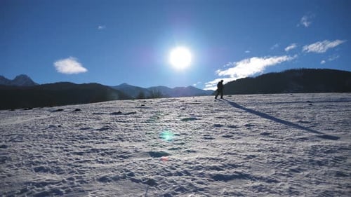 Unrecognizable Guy Goes Nordic Walking with Sticks on Snowy Meadow at Sunny Day. Young Hiker Treks