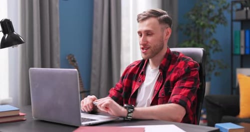 Smiling Student Boy Chats on Video Chat on Laptop with College Friends