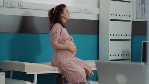 Pregnant Woman Sitting in Hospital Exam Room