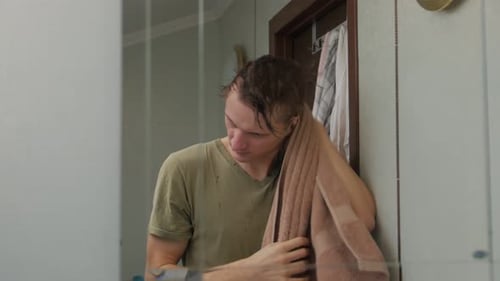Man Dries and Combs Wet Hair in Mirror
