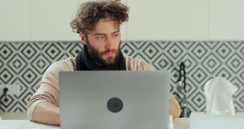 Sick Bearded Man Blows His Nose Into a Paper Napkin While Working Remotely at Home