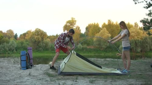Couple Setting Up Camping Tent Near Lake