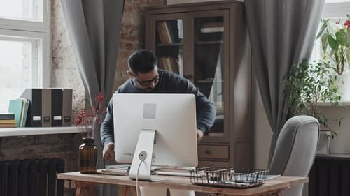 Middle Eastern Man Sitting at Desk and Video Calling on Computer
