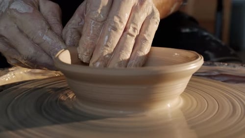 Close-up of Bowl Spinning on Throwing-wheel and Potter' Hands Shaping Clay in Workshop