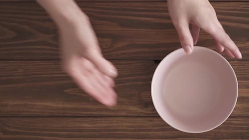 Hands Placing Pastel Bowls on Wooden Table