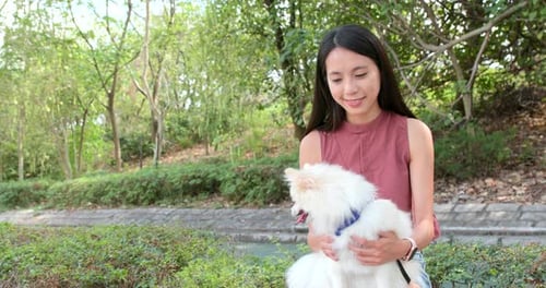 Woman Holding her White Dog in a Park