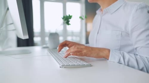 Woman Typing on Keyboard in Bright Office