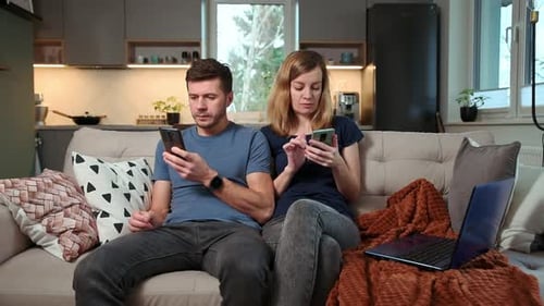 Couple Using Smartphones on Couch in Modern Home