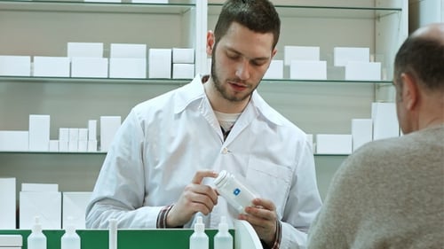Un jeune pharmacien conseille des pilules, un client senior d'une pharmacie