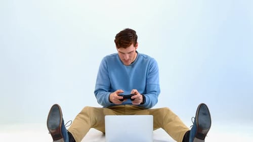 Man Plays Game with Controller by Laptop