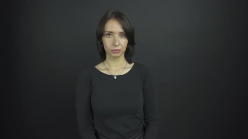 Disappointed Brunette Stands Under Electric Light in Studio