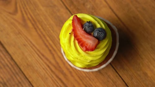 Top View of a Cupcake with Yellow Sweet Cream is Spinning on a Blue Background