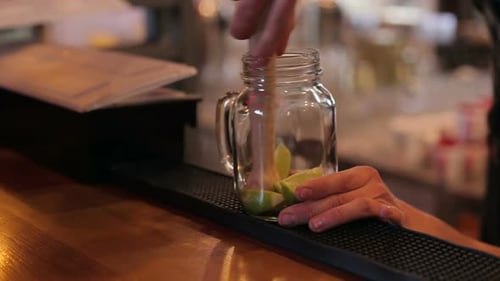 Closeup of Bartender Making Mojito Cocktails with Lime Mint and Rum in Bar