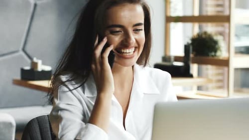 Smart and Charming Business Lady Talking on Phone While Sitting in Modern Cafe