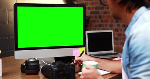 Man Uses Tablet Near Green Screen Monitor