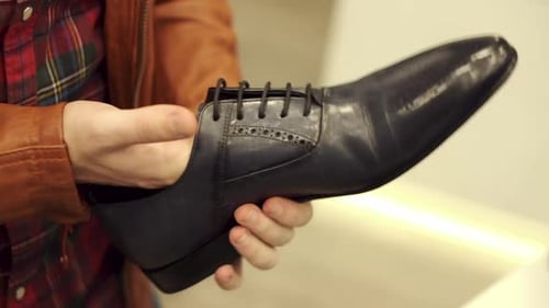 Man Examining Black Leather Dress Shoe