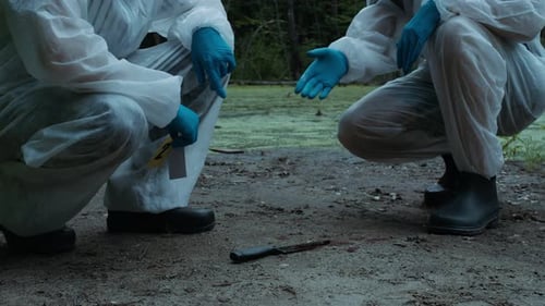 Figures Examine Knife Evidence Outdoors