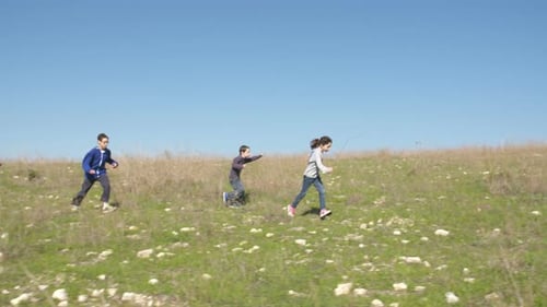 Young kids running together on green hills outdoors in nature