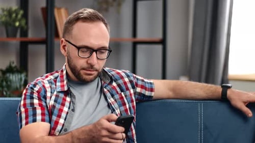 Man Using Mobile Phone Relaxing on Blue Couch