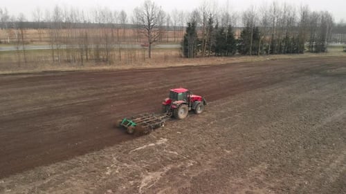 Un tracteur aérien cultive des terres sur des terres agricoles près de l'autoroute