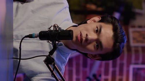 Dark Haired Young Adult Broadcasting Into Microphone
