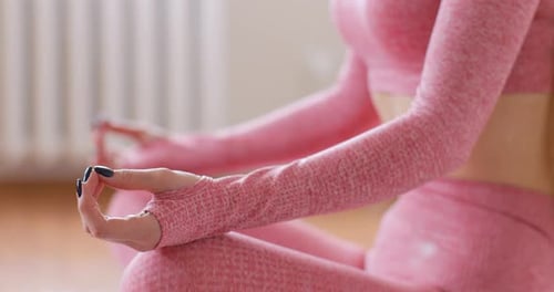 Happy woman in pink suit doing morning practice in modern living room. Detail shot moving hands