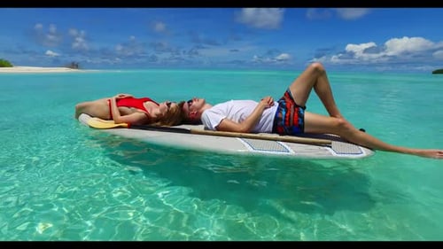 Young couple in love on tranquil lagoon beach wildlife by blue water with white sandy background of