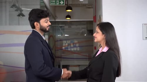 Männliche und weibliche indische Unternehmer beim Händeschütteln