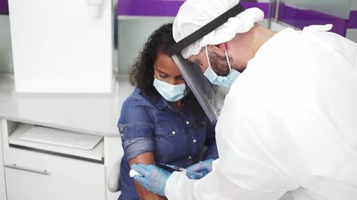Male nurse giving injection to black female patient