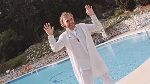 Hombre sonriente bailando en blanco por piscina