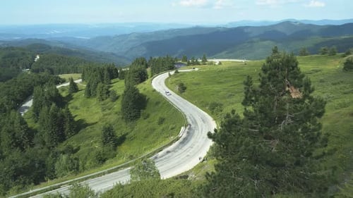 Aerial View of Silver Sedan Driving Through Forest Mountain Road