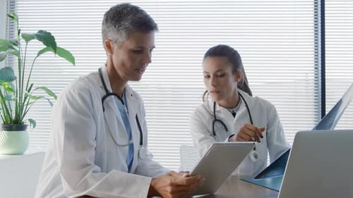 Doctors Reviewing X-Ray and Tablet in Office