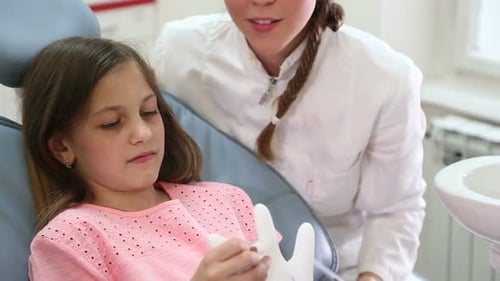 Close up of pretty girl and dentist having fun playing with rubber glove