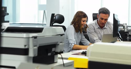 Two Colleagues Working Together at Desk in Urban Office