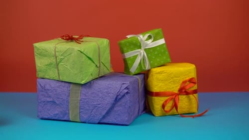Colorful Presents Being Picked Up off Blue Table