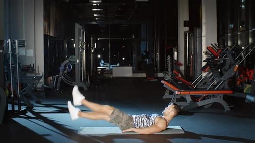 Sportler arbeitet an Rumpfstärke und macht Scissor Kick Flutter Kick auf Fußmatte im Fitnessstudio