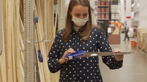 Woman Wearing a Protective Mask in Building Store Chooses Hand Saw