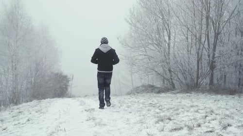 Anonymous man walking on snowy path