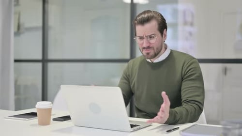 Frustrated Man Working on a Laptop in Office
