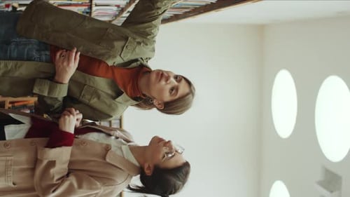 Young Women Discussing Book in Library
