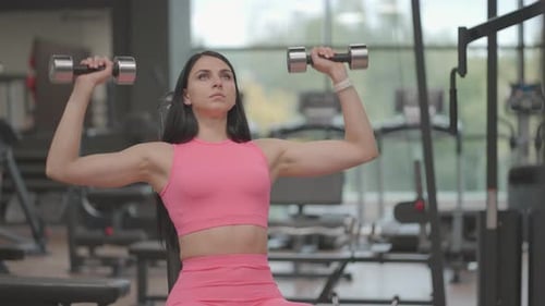 Woman Lifting Dumbbells in Gym for Strength Training