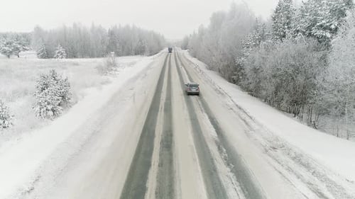 Truck drive along the road through the winter forest