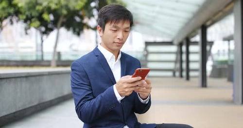 Young Adult in Suit Using Mobile Phone Outdoors